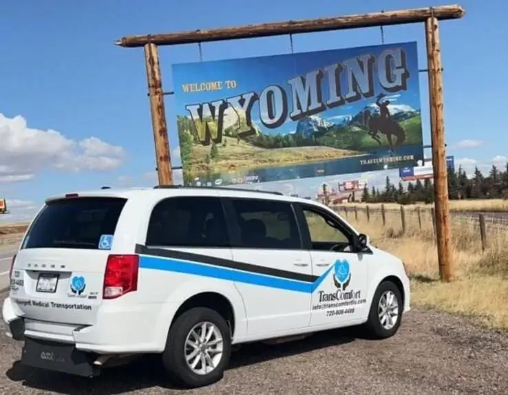 A TransComfort van parked at the Welcome to Wyoming sign at the state line.