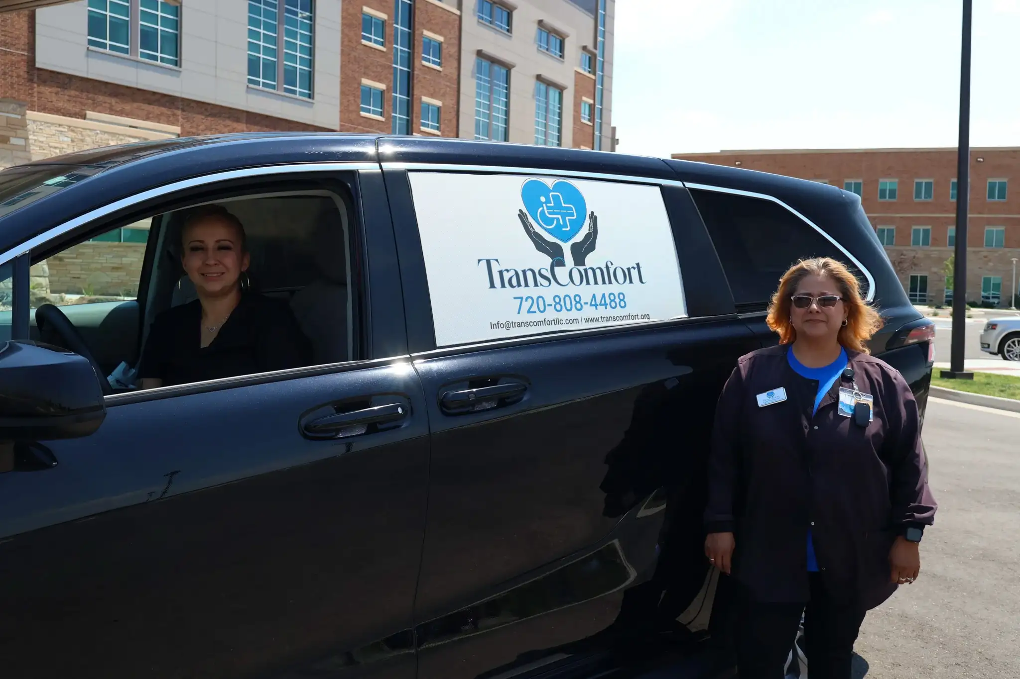 Two TransComfort crew members at a van, one at the wheel and one standing beside the company livery.